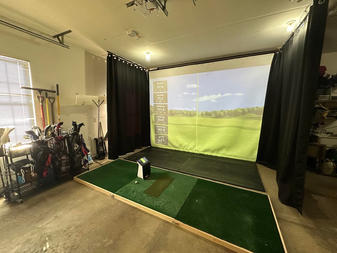 A real garage converted into a golf simulator bay with impact screen and launch monitor
